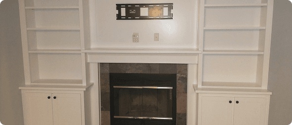 Custom white built-in cabinetry beside fireplace